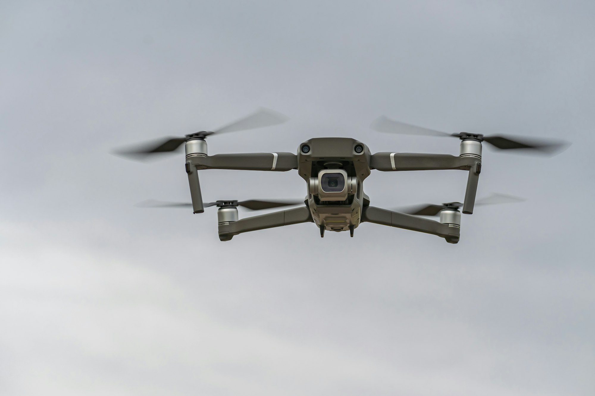 Professional quadcopter flying high in the gray sky